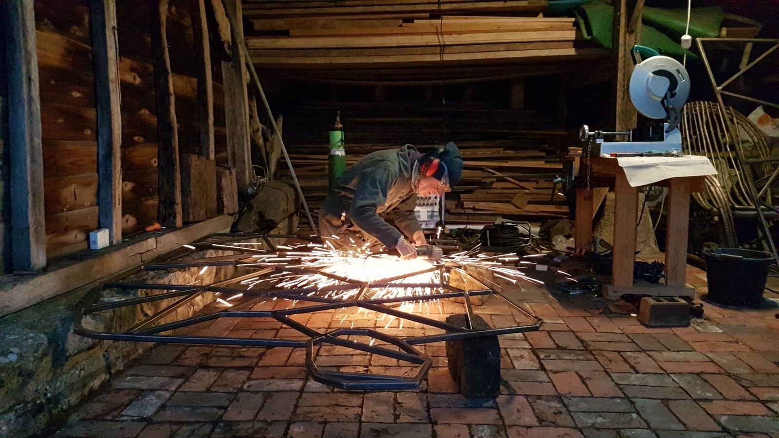 Michael Joseph cutting a steel sculpture in his studio, sparks flying